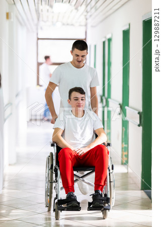 Young Male Patient in Wheelchair Assisted by Female Medical Professional Young Male Patient in Wheelchair Assisted by Female Medical Professional 129887211