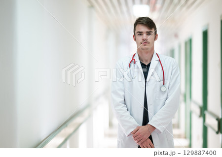 Doctor Standing in Hospital Hallway.Young male doctor standing confidently in a hospital corridor with a stethoscope. Medical professionalism concept. 129887400