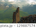 Ancient architecture and ruins against mountain background . Remains of a destroyed tower . North Ossetia-Alania , Russia 129887574