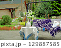 Apple blossoms on a table in front of a sofa swing in the courtyard of a country house. 129887585