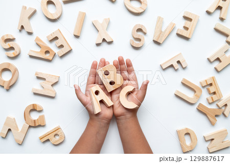 Child hands holding wooden alphabet letters on white background Child hands holding wooden alphabet letters on white background 129887617