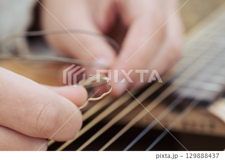 Macro shot of torm guitar string in hands of a guitarist. Changing strings in the guitar 129888437