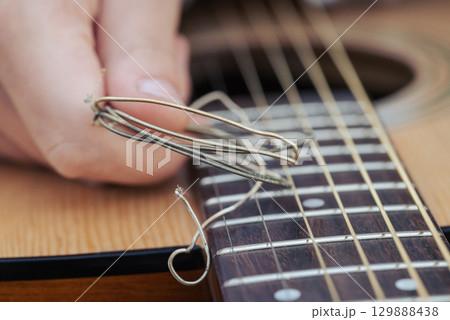 Old used guitar strings near new changed ones on the guitar. Concept of changing bad old strings on acoustic guitar 129888438