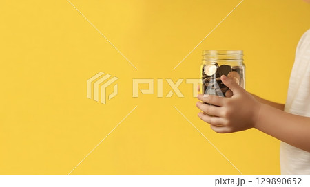Child giving coins from jar on yellow background charity concept 129890652