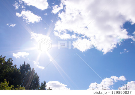Bright sun and blue sky with clouds. Concept of abnormal heat Bright sun and blue sky with clouds. Concept of abnormal heat 129890827