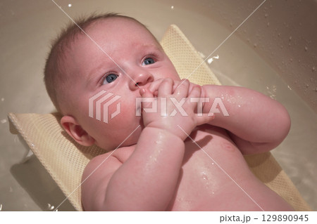 Infant baby boy washed in small bath tub, view from above 129890945