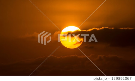 Sun flare above horizon with clouds and red-orange sky creating bold contrast and glowing atmospheric effect 129891067