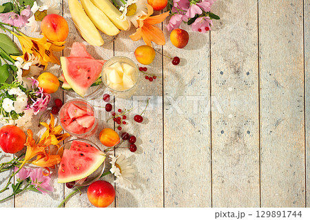 Autumn-summer banner with fruit drinks. Still life with flowers, lilies, mint, mallow, daisies, apples, melons, cherries and watermelon on a sunny table. Abstract floral composition, background, 129891744