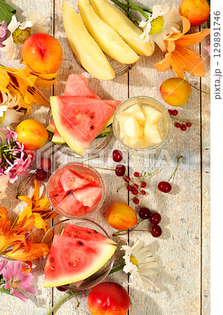 Autumn-summer banner with fruit drinks. Still life with flowers, lilies, mint, mallow, daisies, apples, melons, cherries and watermelon on a sunny table. Abstract floral composition, background, Autumn-summer banner with fruit drinks. Still life with flowers, lilies, mint, mallow, daisies, apples, melons, cherries and watermelon on a sunny table. Abstract floral composition, background, 129891746