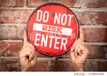 Red Circular Warning Sign with Text Do Not Risk Enter Held Against Brick Wall Red Circular Warning Sign with Text Do Not Risk Enter Held Against Brick Wall 129891890