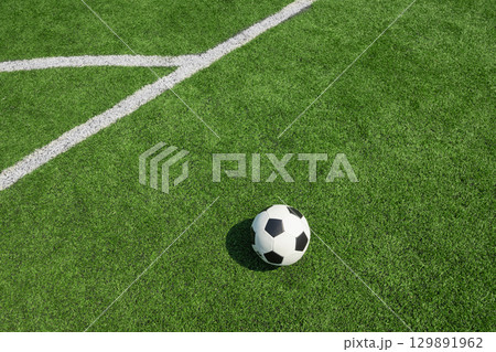 Soccer ball on green grass field with white line. Football stadium background. 129891962