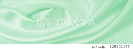 Smooth elegant green silk or satin luxury cloth texture as abstract background. Luxurious background design 129892147