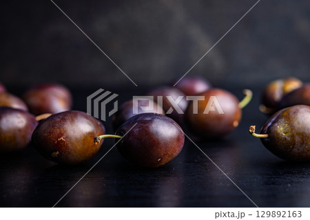 Ripe plums on black table. 129892163