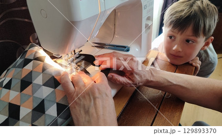 Child watching sewing on machine - DIY crafting, family bonding, handmade textiles, slow living home studio, sustainable fashion learning moment Child watching sewing on machine - DIY crafting, family bonding, handmade textiles, slow living home studio, sustainable fashion learning moment 129893370