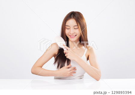 Hair treatment and flowing hair are featured as a woman brushes calmly, expressing wellness, self-care, and the elegance of silky strands in a spa or beauty routine. isolated studio white background Hair treatment and flowing hair are featured as a woman brushes calmly, expressing wellness, self-care, and the elegance of silky strands in a spa or beauty routine. isolated studio white background 129893394