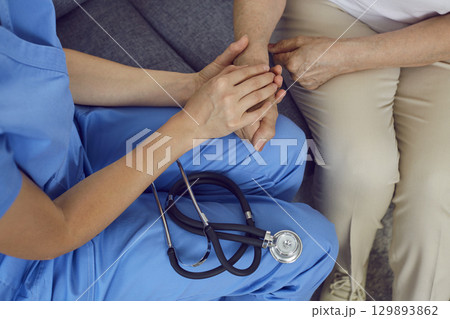 Doctor with stethoscope holding old woman by hand, showing compassion and supporting her Doctor with stethoscope holding old woman by hand, showing compassion and supporting her 129893862