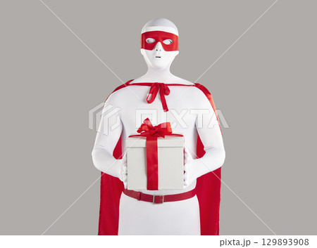 Studio portrait of a man disguised in a super hero costume holding a present box 129893908