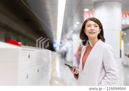 ホームでスマホを使う女性 129894004