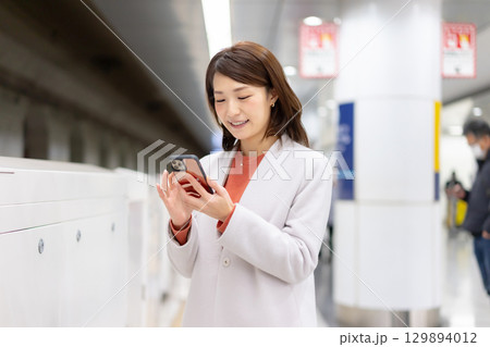 ホームでスマホを使う女性 129894012