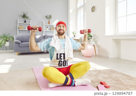Funny happy sportsman sitting to exercise with dumbbell for strong muscle building, playful comedian Funny happy sportsman sitting to exercise with dumbbell for strong muscle building, playful comedian 129894787