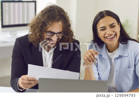 Two happy colleagues friends having fun and laughing at funny jokes at work in office Two happy colleagues friends having fun and laughing at funny jokes at work in office 129894793