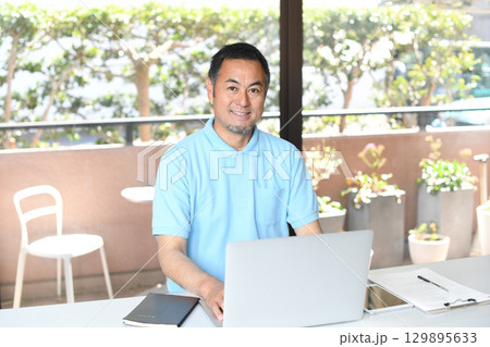 PCで事務作業をする笑顔のアジア人男性 PCで事務作業をする笑顔のアジア人男性 129895633