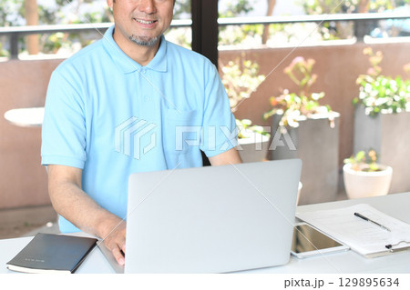 PCで事務作業をする笑顔のアジア人男性 PCで事務作業をする笑顔のアジア人男性 129895634