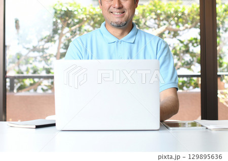 PCで事務作業をする笑顔のアジア人男性 PCで事務作業をする笑顔のアジア人男性 129895636