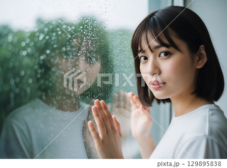 雨の日の窓辺で過ごす女性のポートレート 129895838
