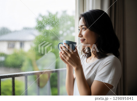 雨の日の窓辺で過ごす女性のポートレート 129895841