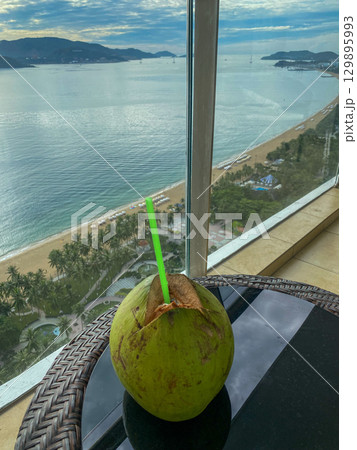 Fresh coconut drink with sea and beach view from balcony 129895993