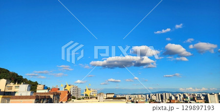 Sky view adorned with towering buildings, captured from below. The perspective showcases the majestic structures blending harmoniously with stunning clouds and a vibrant, clear sky. 129897193
