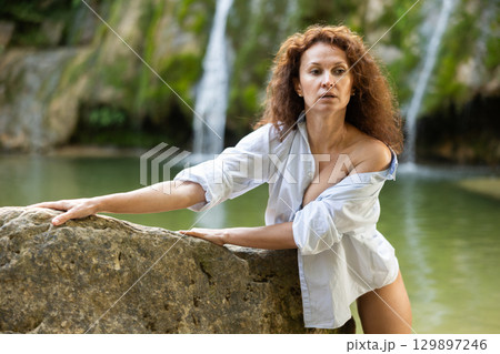 Portrait of half-naked woman in white shirt and white panties against the background of tropical waterfall Portrait of half-naked woman in white shirt and white panties against the background of tropical waterfall 129897246
