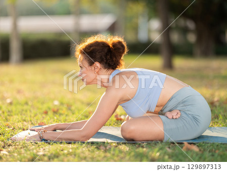 Early morning outdoor yoga class - woman in downward dog pose Early morning outdoor yoga class - woman in downward dog pose 129897313