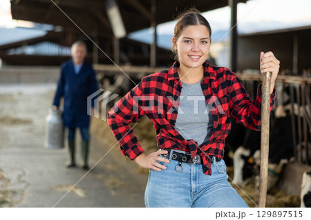 Smiling girl farmer posing in outdoor cowshed at livestock farm 129897515