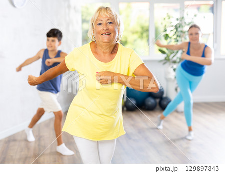 Three generations of mother, grandmother and teen son learn sports Latin American dances 129897843