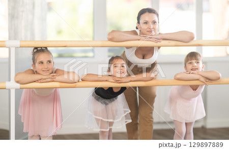 Choreography teacher posing with little girl students in ballet studio 129897889
