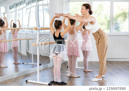 Girls in ballet class perform first position with correction of female mentor 129897890