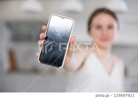 Mobile phone held in hand against blurred background Mobile phone held in hand against blurred background 129897921