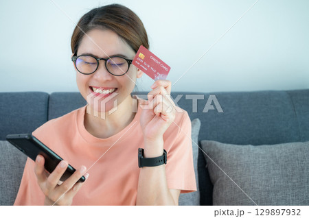 Asian woman having feels good after buying somethings online by credit card. A credit card is a type of credit facility, provided by banks that allow customers to borrow funds. 129897932