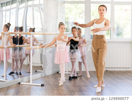 Girl students of choreographic school look at woman teacher and repeat movements after her 129898077
