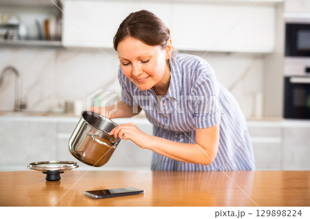 Portrait of a housewife preparing soup in a pot in kitchen 129898224