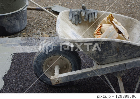 Wheelbarrow is filled with dirt and a pair of gloves 129899396