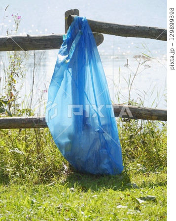 Blue plastic bag is hanging from a wooden fence Blue plastic bag is hanging from a wooden fence 129899398