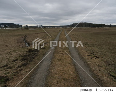 Road in a field with a cloudy sky in the background Road in a field with a cloudy sky in the background 129899443