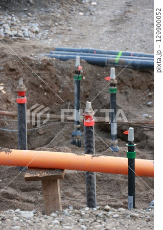 Bunch of pipes are in the dirt with orange cables 129900052