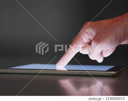 Hand pointing at a tablet screen 129900053