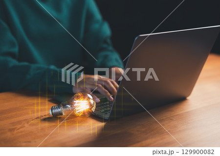 Creative concept of innovation with a glowing light bulb and a person typing on a laptop, symbolizing new ideas and digital thinking, new business plan, motivation, inspiration. 129900082