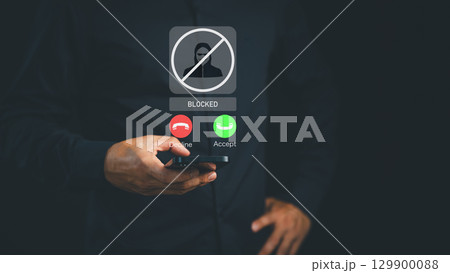Smartphone screen shows a hacker icon and blocked symbol as a user blocks a scam call, highlighting the concept of mobile security, data protection, and preventing cyber fraud and suspicious threats. Smartphone screen shows a hacker icon and blocked symbol as a user blocks a scam call, highlighting the concept of mobile security, data protection, and preventing cyber fraud and suspicious threats. 129900088