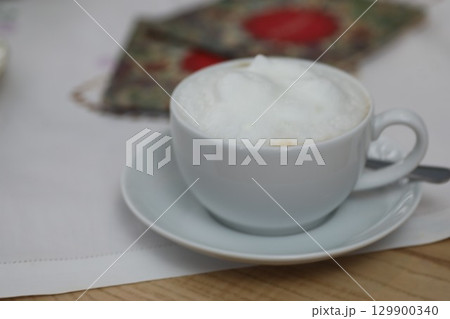 White coffee cup with foam on top sits on a white saucer White coffee cup with foam on top sits on a white saucer 129900340